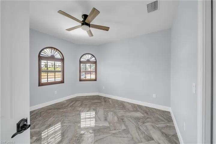 Empty room featuring visible vents, baseboards, and a ceiling fan