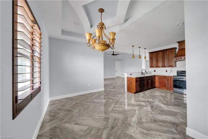 Kitchen featuring open floor plan, a peninsula, stainless steel range with electric cooktop, a raised ceiling, and a sink