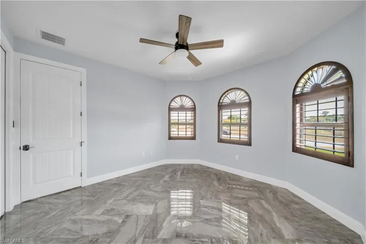 Unfurnished room with marble finish floor, visible vents, baseboards, and ceiling fan
