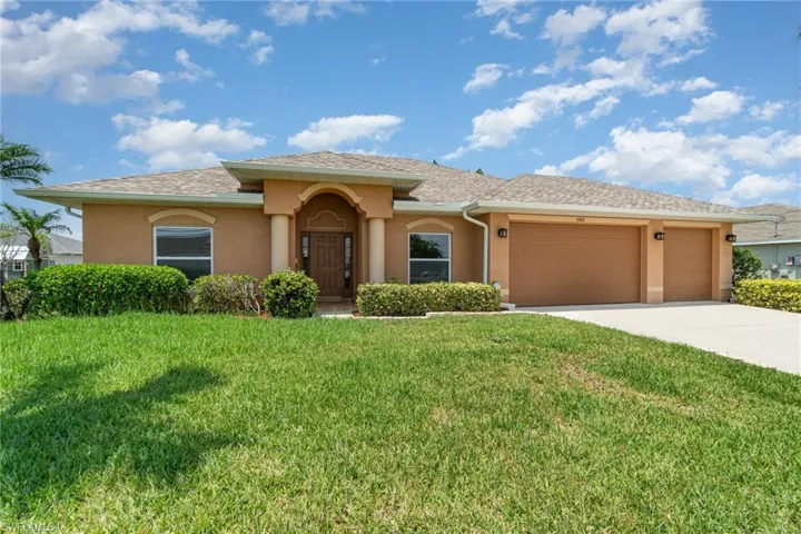 View of front of property with stucco siding, an attached garage, driveway, and a front lawn