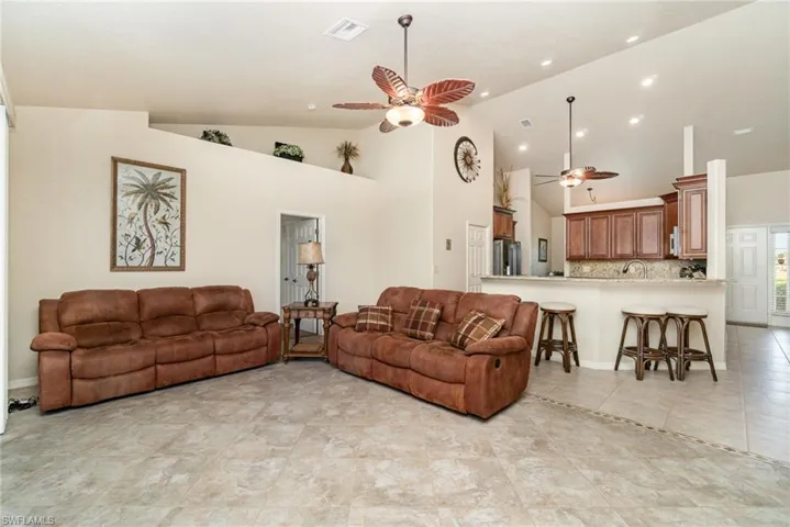 Living room with ceiling fan, high vaulted ceiling, and recessed lighting