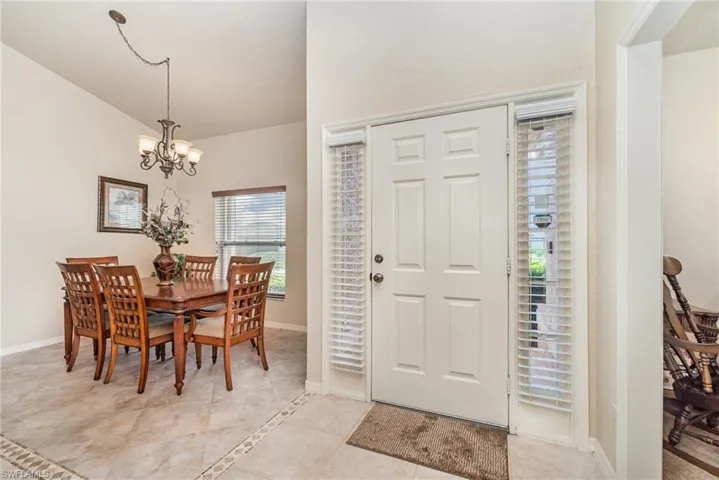 Dining room with a chandelier, light tile patterned floors, and baseboards