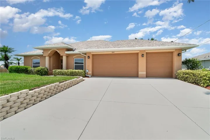 View of front of house featuring stucco siding, a garage, driveway, and a front yard