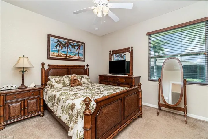 Bedroom with light colored carpet, baseboards, and ceiling fan