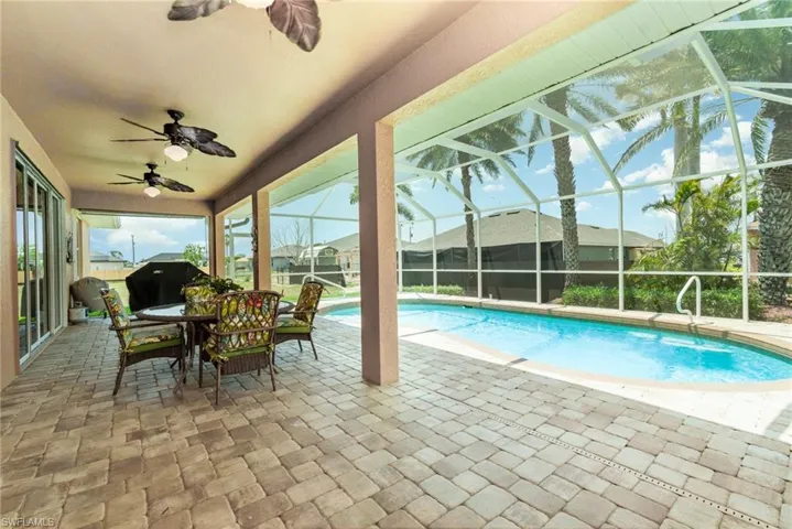 Outdoor pool featuring a patio, ceiling fan, and glass enclosure