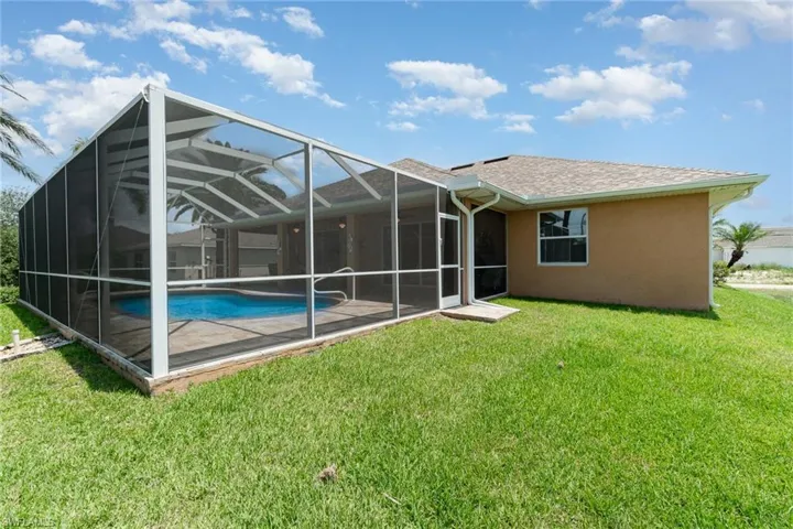 Back of property with an outdoor pool, a yard, stucco siding, a shingled roof, and glass enclosure