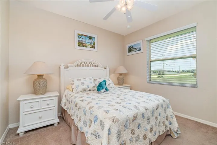 Bedroom featuring light carpet, baseboards, and a ceiling fan