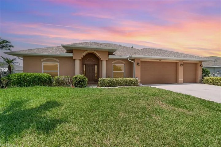 View of front of house with an attached garage, stucco siding, driveway, a yard, and roof with shingles