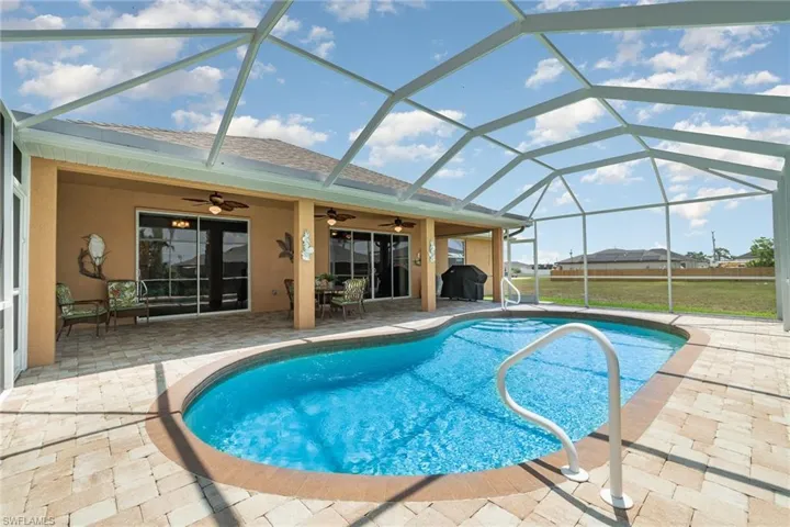Outdoor pool featuring a patio area, ceiling fan, and glass enclosure