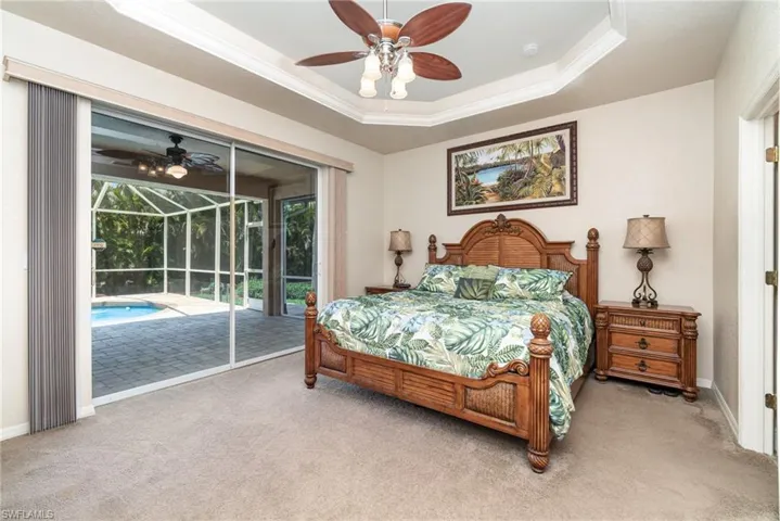 Carpeted bedroom with access to outside, a sunroom, crown molding, a raised ceiling, and baseboards