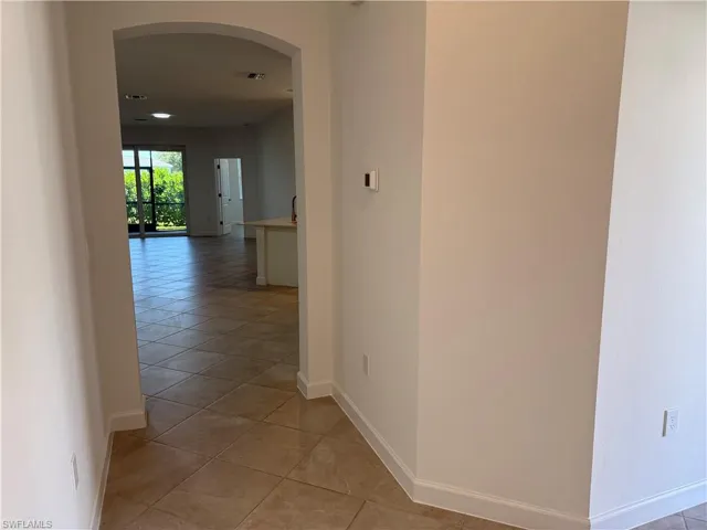 Arched architectural passage featuring neutral-toned tile flooring throughout the open-concept layout and recessed lighting