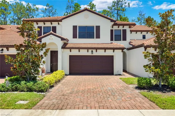 Front view of this Mediterranean style house, tile roof, paver driveway, and 2 car garage