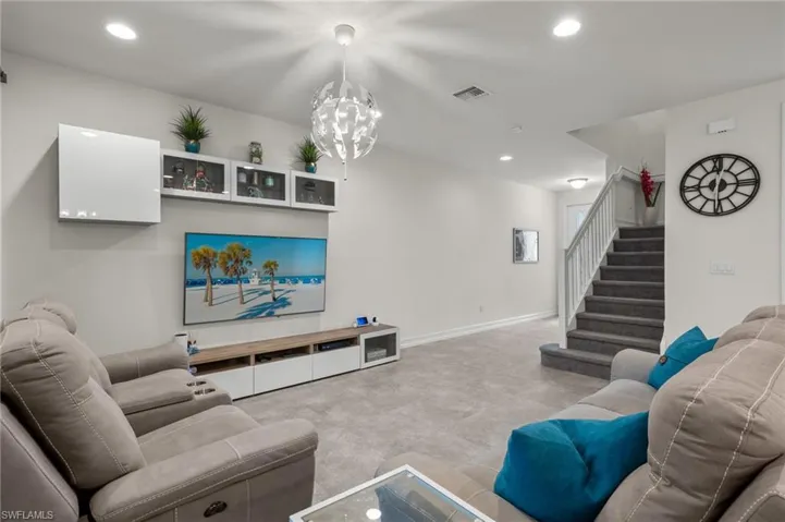 Living room with spacious front entrance, and carpeted stairs to the second level