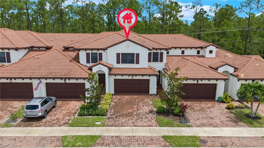 Front view of this Mediterranean style Townhome with tile roof and paver driveway