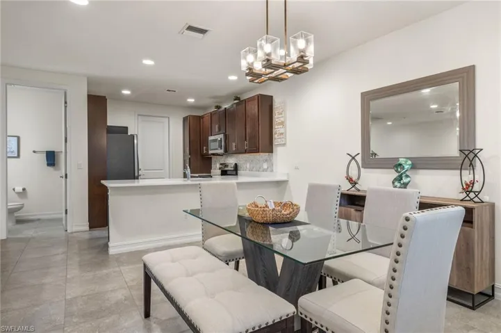 Open concept dining room featuring ample space and lighting with half bath on main level.