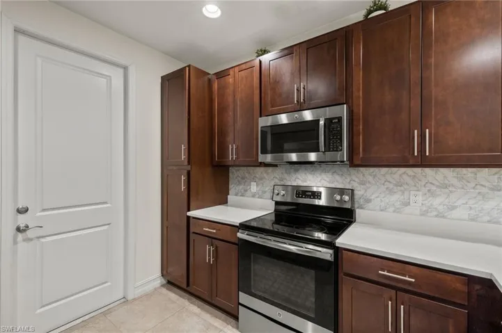 Kitchen with dark cabinetry, pleasing backsplash, with white quartz counters