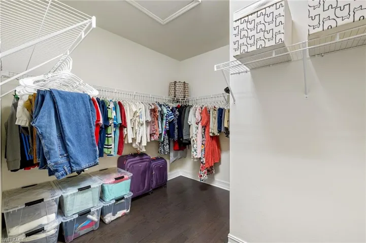 Spacious Owners walk in closet featuring hardwood floors