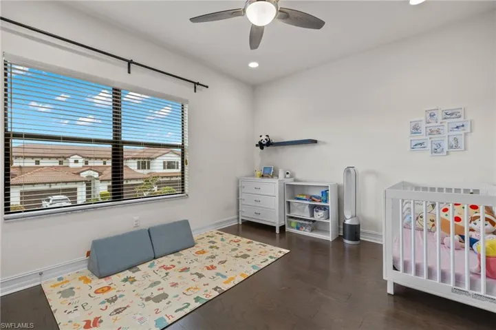 Bedroom two with ample lighting, ceiling fan, walk in closet and dark hardwood floors
