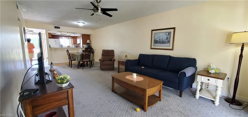 Carpeted living room with a ceiling fan and baseboards