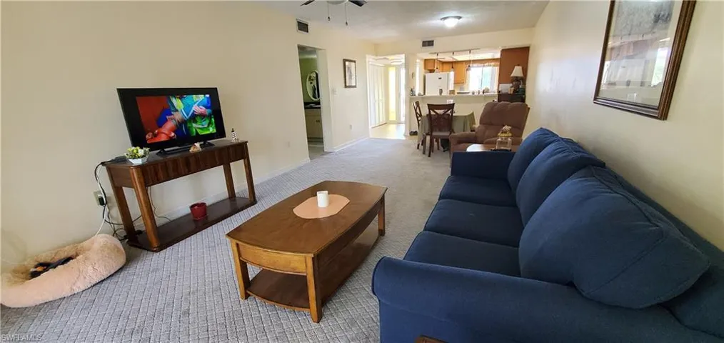 Living room featuring light carpet and a ceiling fan
