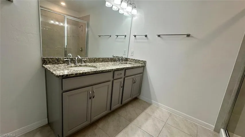 Bathroom with a stall shower, double vanity, and light tile patterned floors