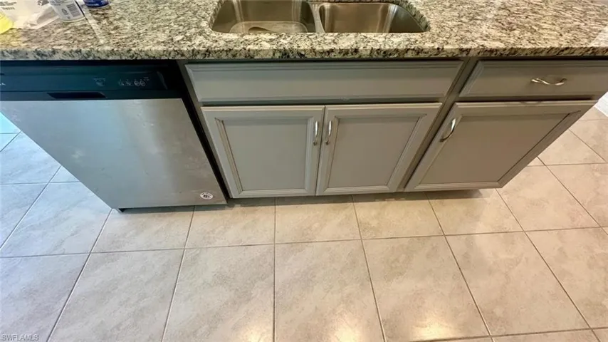 Kitchen view of gray cabinets, stainless steel dishwasher, and light stone countertops