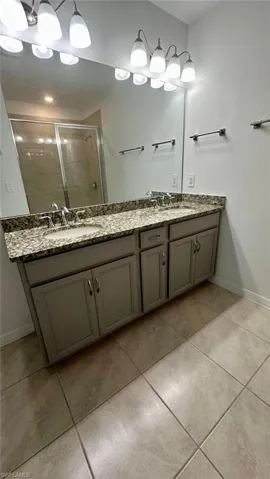 Bathroom featuring a stall shower, double vanity, and light tile patterned floors
