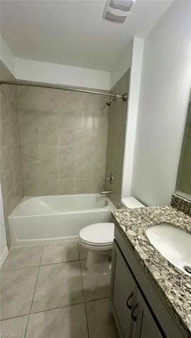 Bathroom with bathtub / shower combination, vanity, and light tile patterned flooring