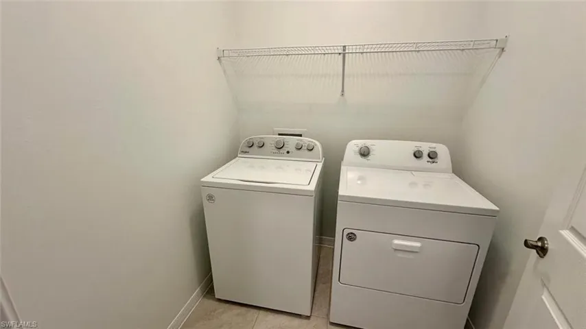 Laundry area with washer and dryer and light tile patterned floors