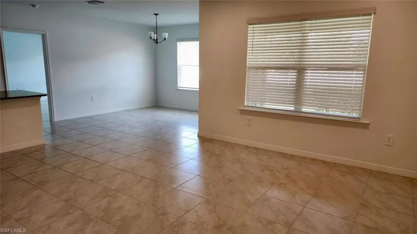 Empty room featuring light tile patterned floors and a chandelier