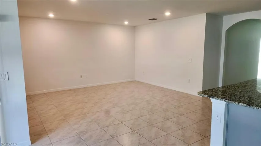 Unfurnished room featuring arched walkways, recessed lighting, and light tile patterned floors