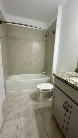 Bathroom featuring shower / tub combination, vanity, and light tile patterned floors