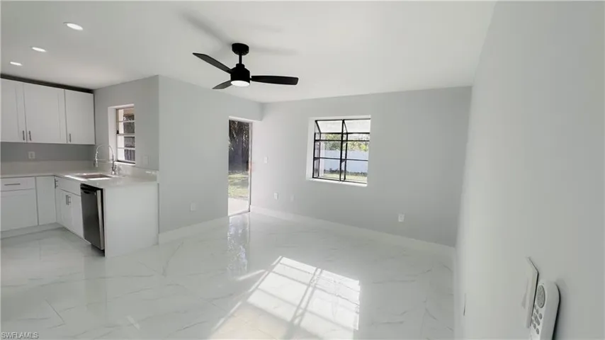 Kitchen featuring ceiling fan, dishwasher, white cabinets, and sink