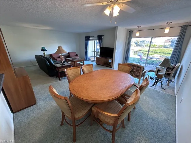 Dining area with ceiling fan, light colored carpet, plenty of natural light, and a textured ceiling