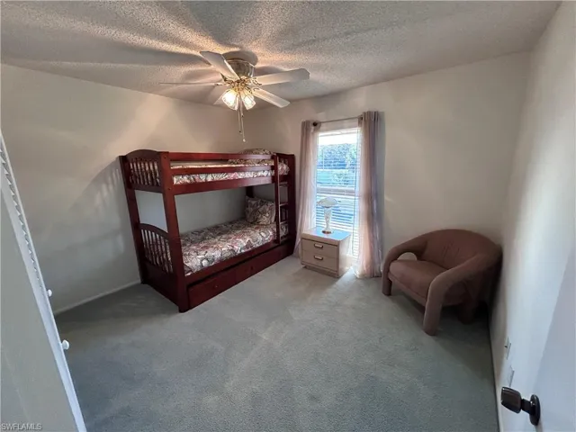Carpeted bedroom with a textured ceiling and ceiling fan