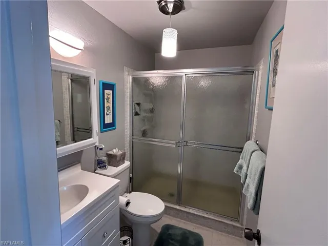 Bathroom featuring vanity, an enclosed shower, tile patterned floors, and toilet