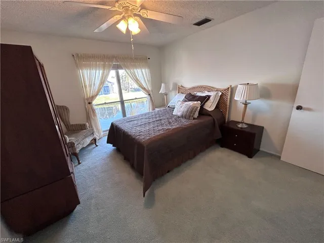 Carpeted bedroom featuring ceiling fan, a textured ceiling, and access to outside