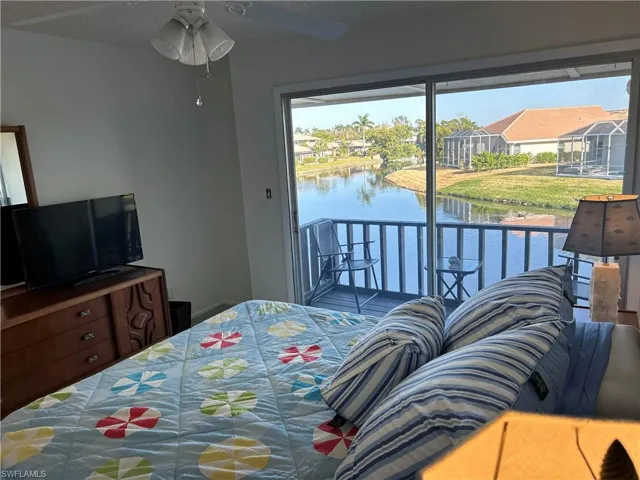 Bedroom featuring a water view, access to exterior, and ceiling fan