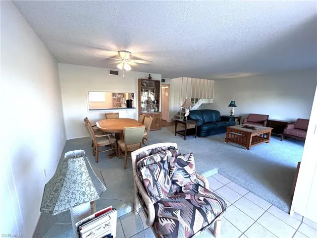 Living room with ceiling fan, light colored carpet, and a textured ceiling