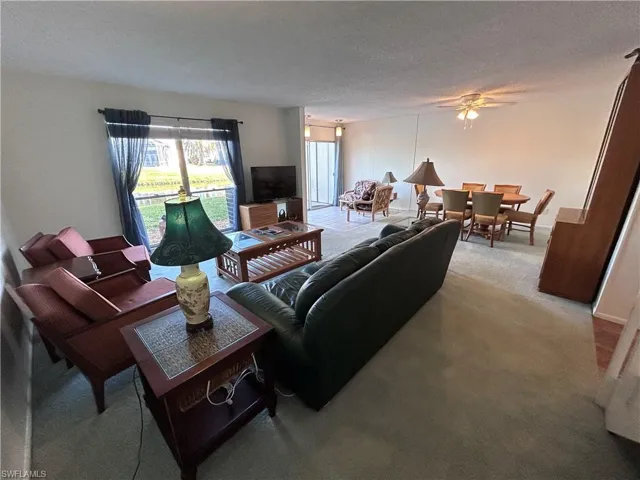 Living room with ceiling fan, light carpet, and a textured ceiling