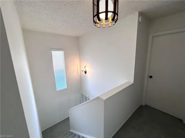 Staircase featuring carpet floors and a textured ceiling