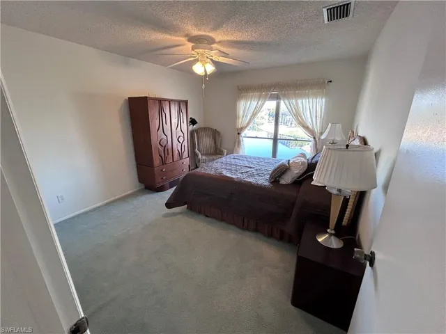 Carpeted bedroom featuring a textured ceiling and ceiling fan