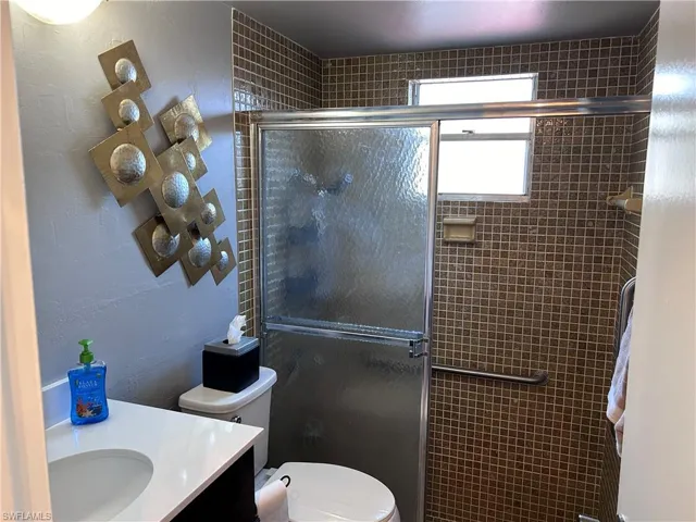 Bathroom featuring vanity, toilet, and an enclosed shower
