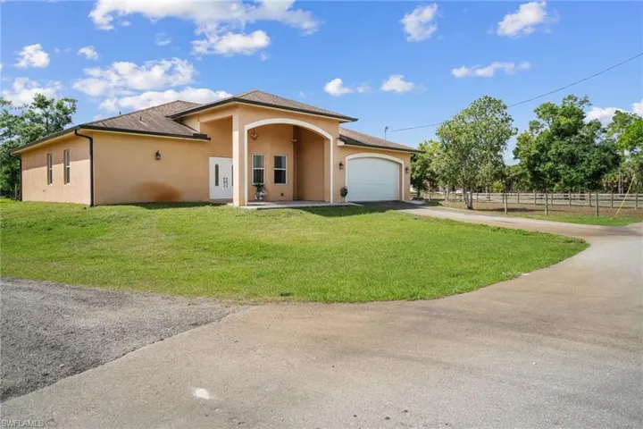 View of front of house with a garage and large paved driveway`