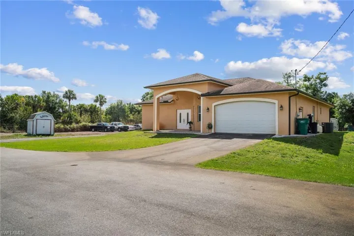 View of front of house with a garage and large paved driveway`