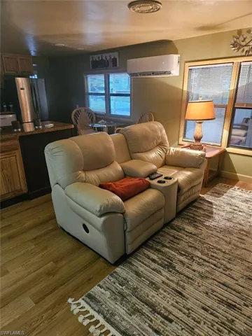 Living room featuring a wall mounted AC and laminate wood like floors