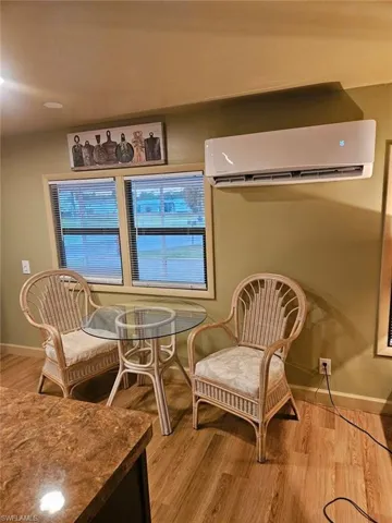 Sitting room with an AC wall unit and light laminate flooring