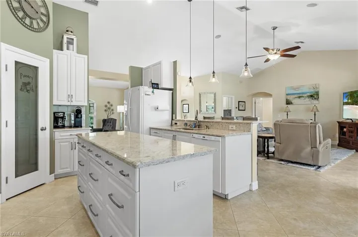 Kitchen featuring white cabinets, high vaulted ceiling, open floor plan, hanging light fixtures, and a center island