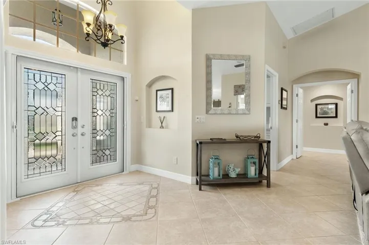 Entryway featuring light tile patterned flooring, high vaulted ceiling, french doors, and arched walkways