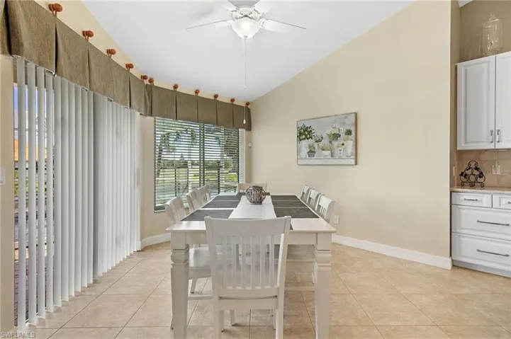 Dining space featuring light tile patterned floors, lofted ceiling, and a ceiling fan